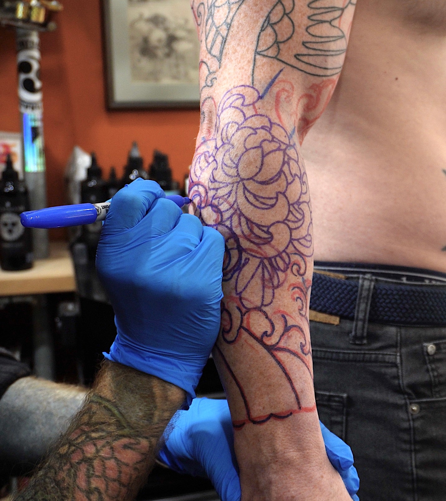 Background and flowers being drawn directly onto the client's arm
